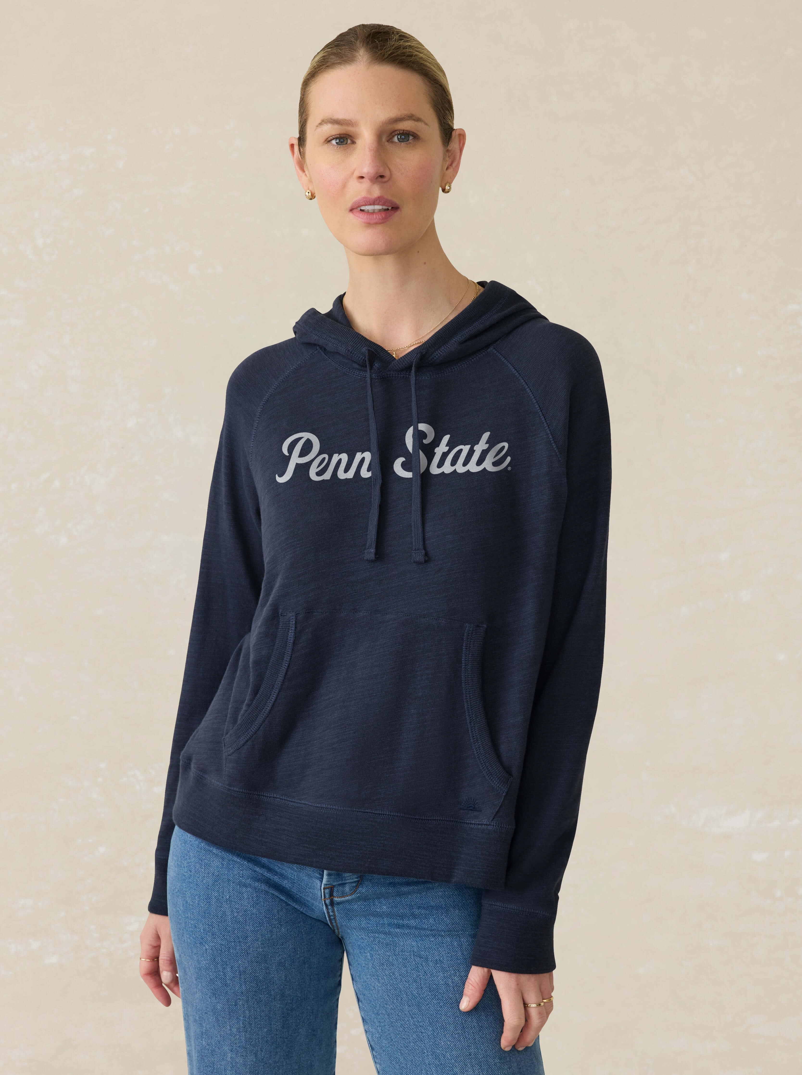 Model is wearing a blue hoodie with Penn State text on the center chest against a beige background