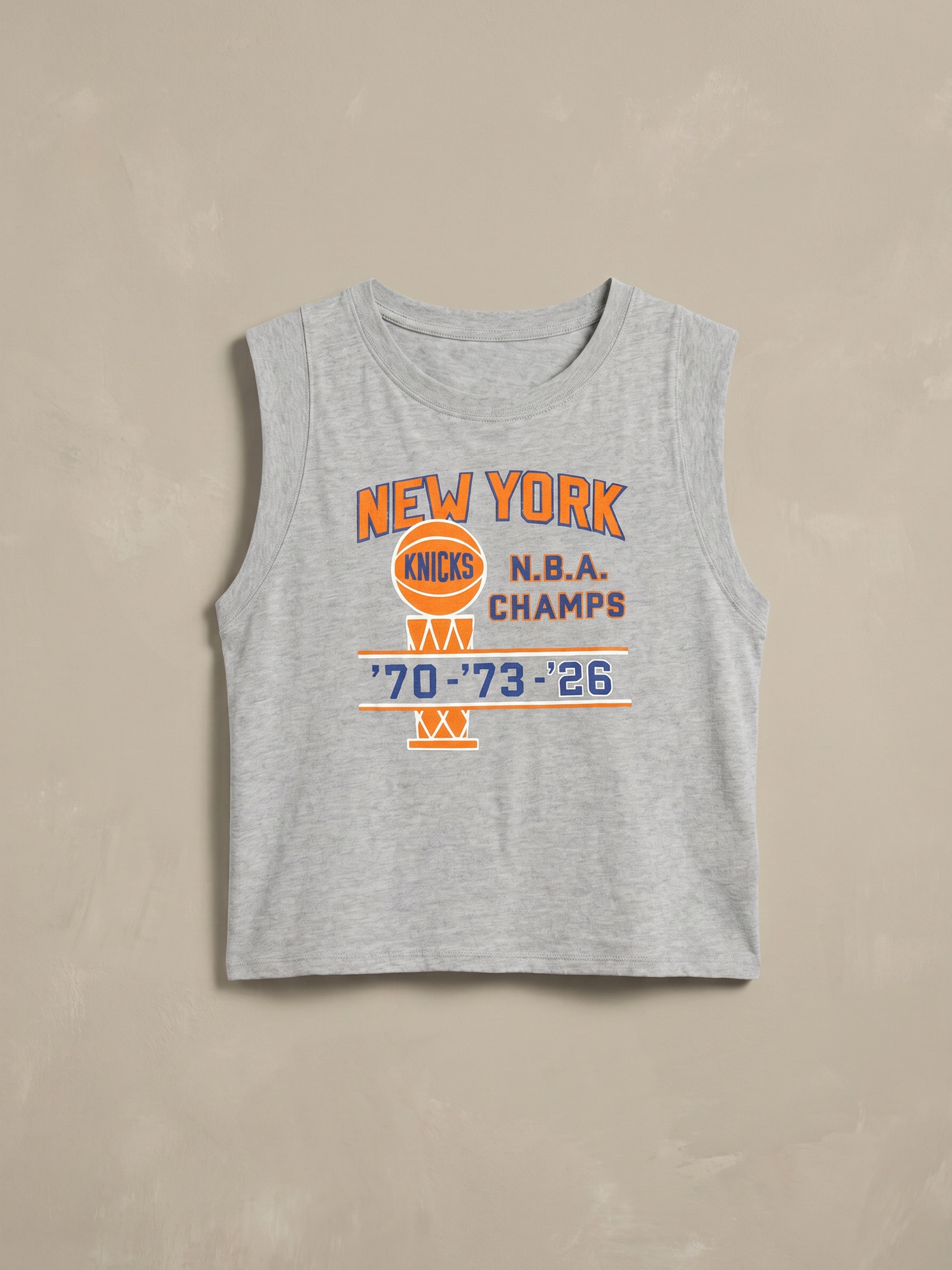 Gray tank top with New York Knicks NBA Champs graphic on the center front against a beige background