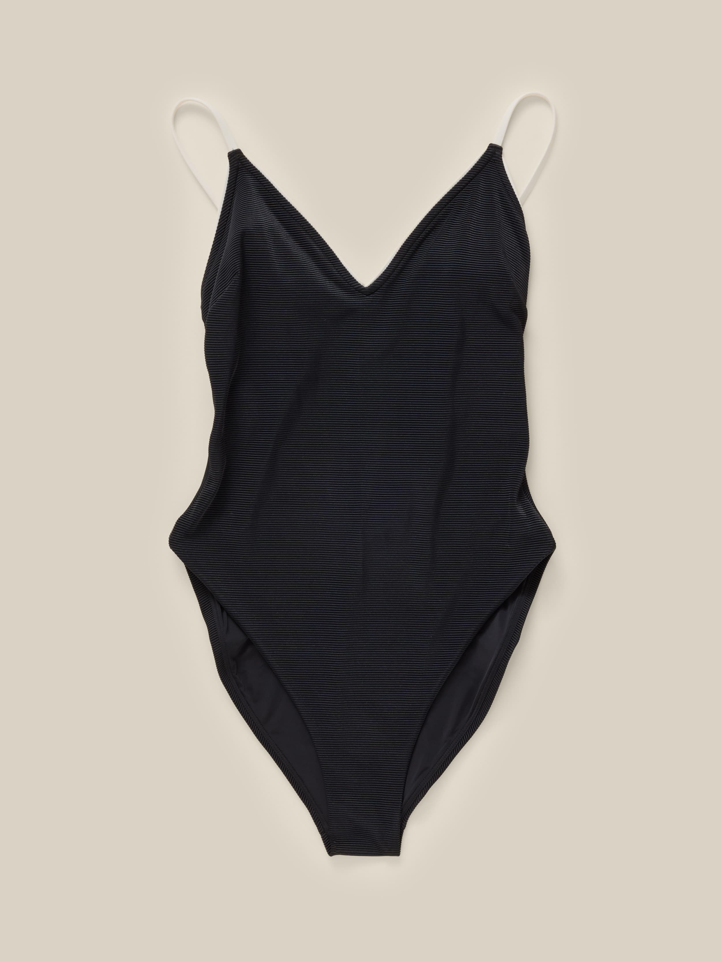 A black one piece swimsuit against a beige background