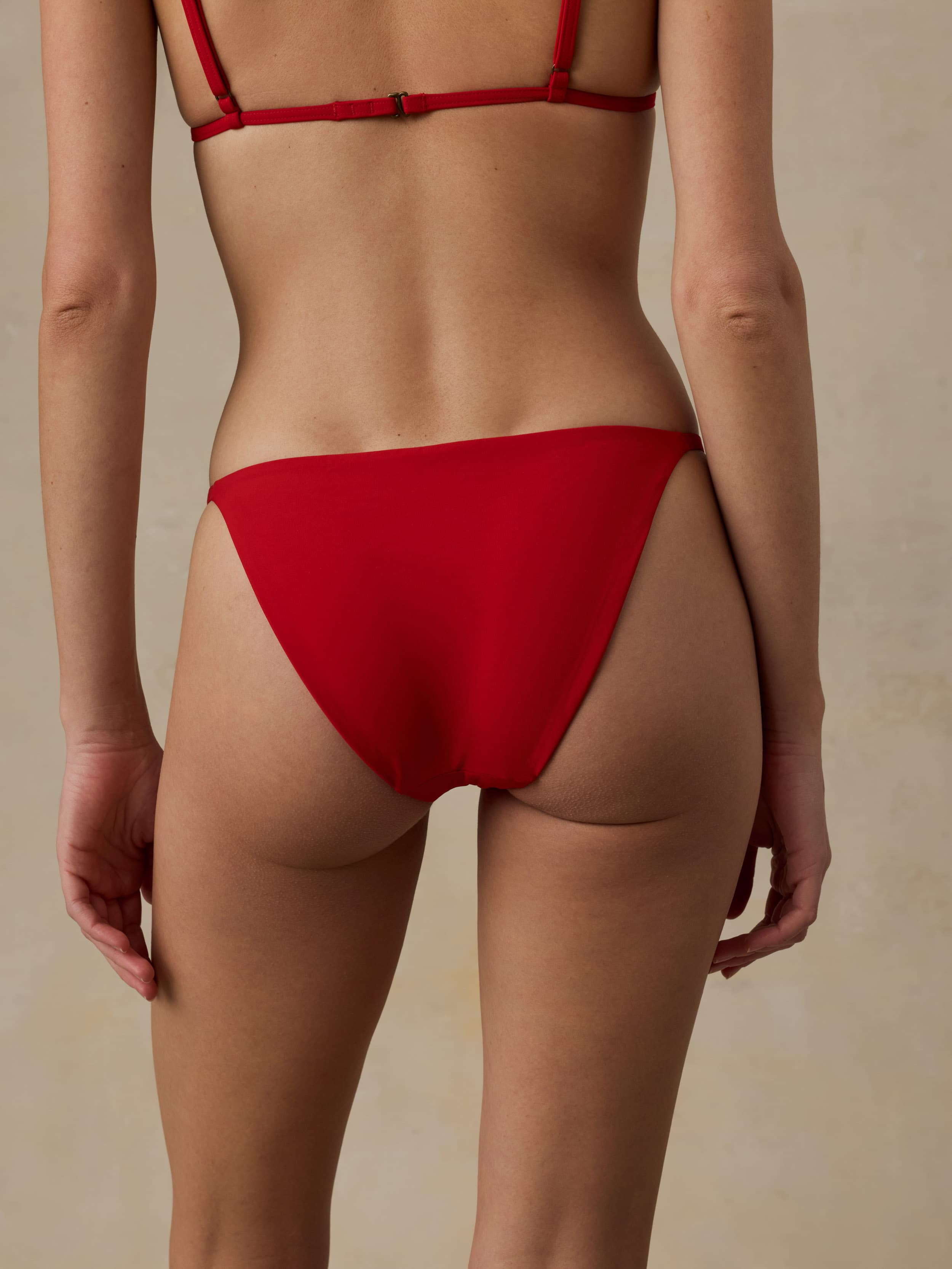 Woman wearing a red bikini against a beige background