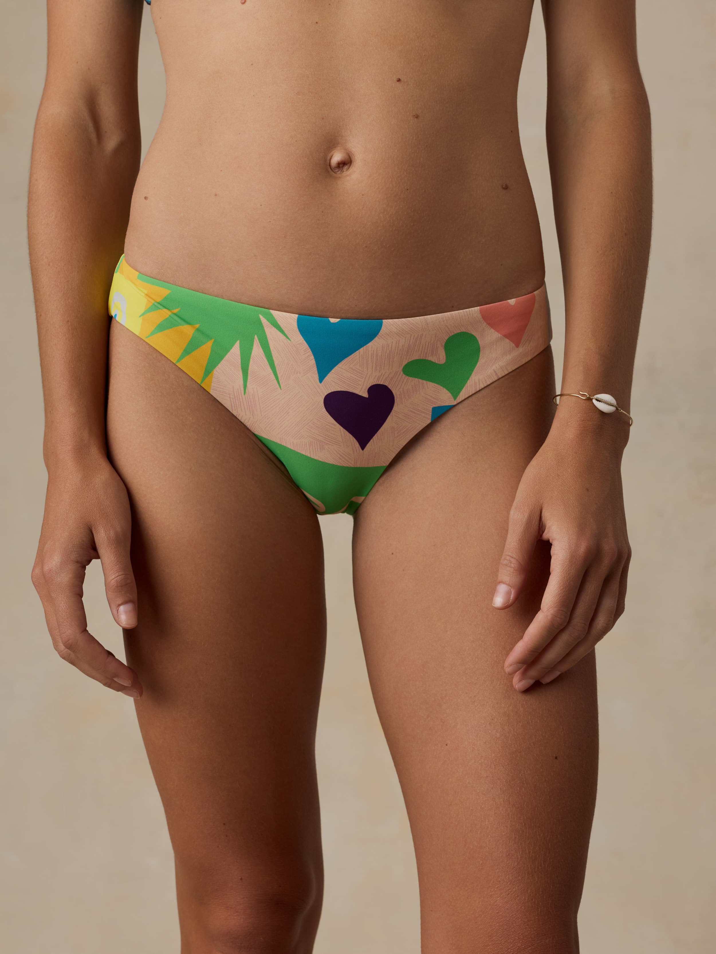Colorful bikini bottom with heart and leaf patterns on a beige background