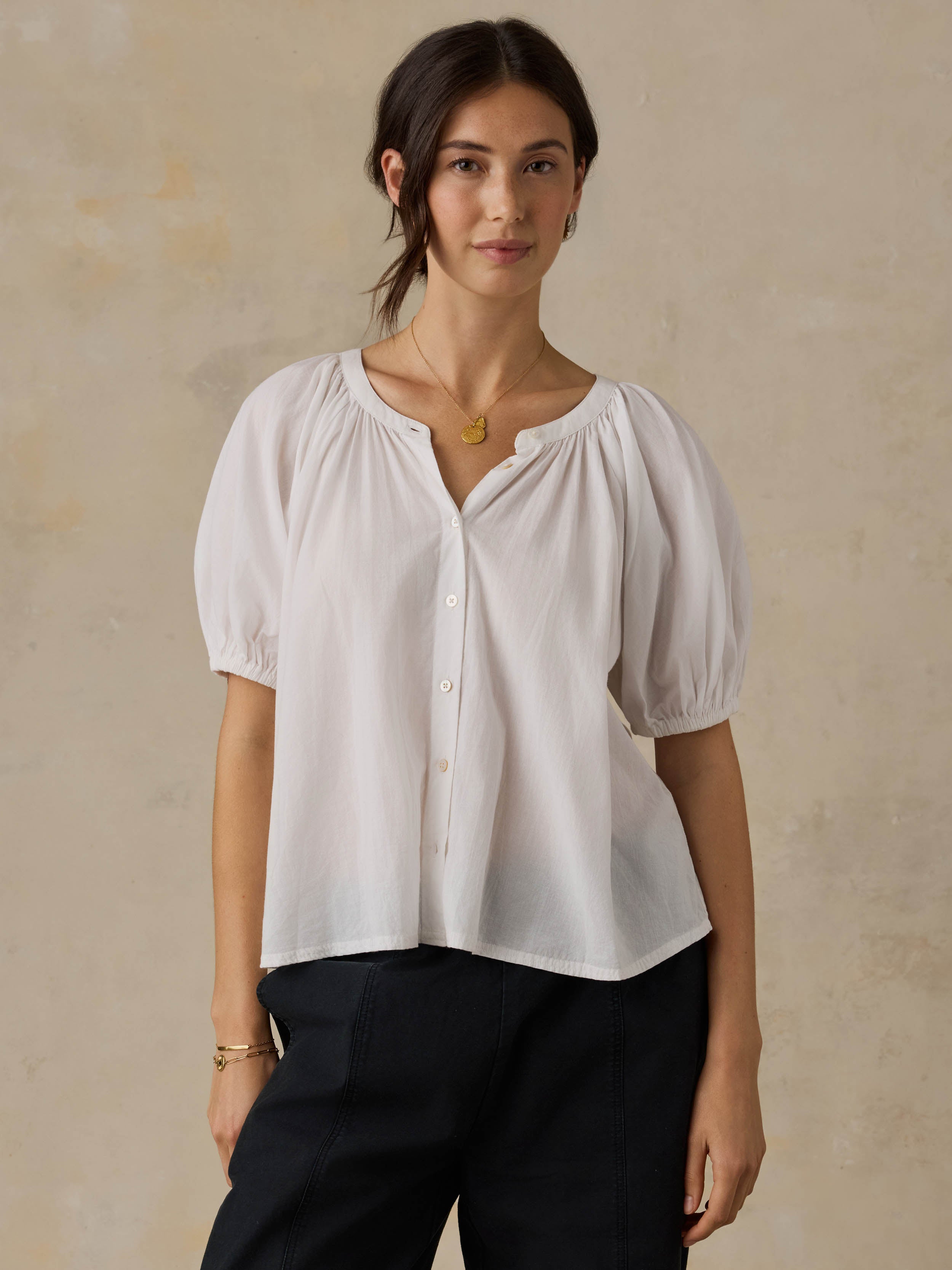 Woman wearing a white blouse with puff sleeves against a beige background