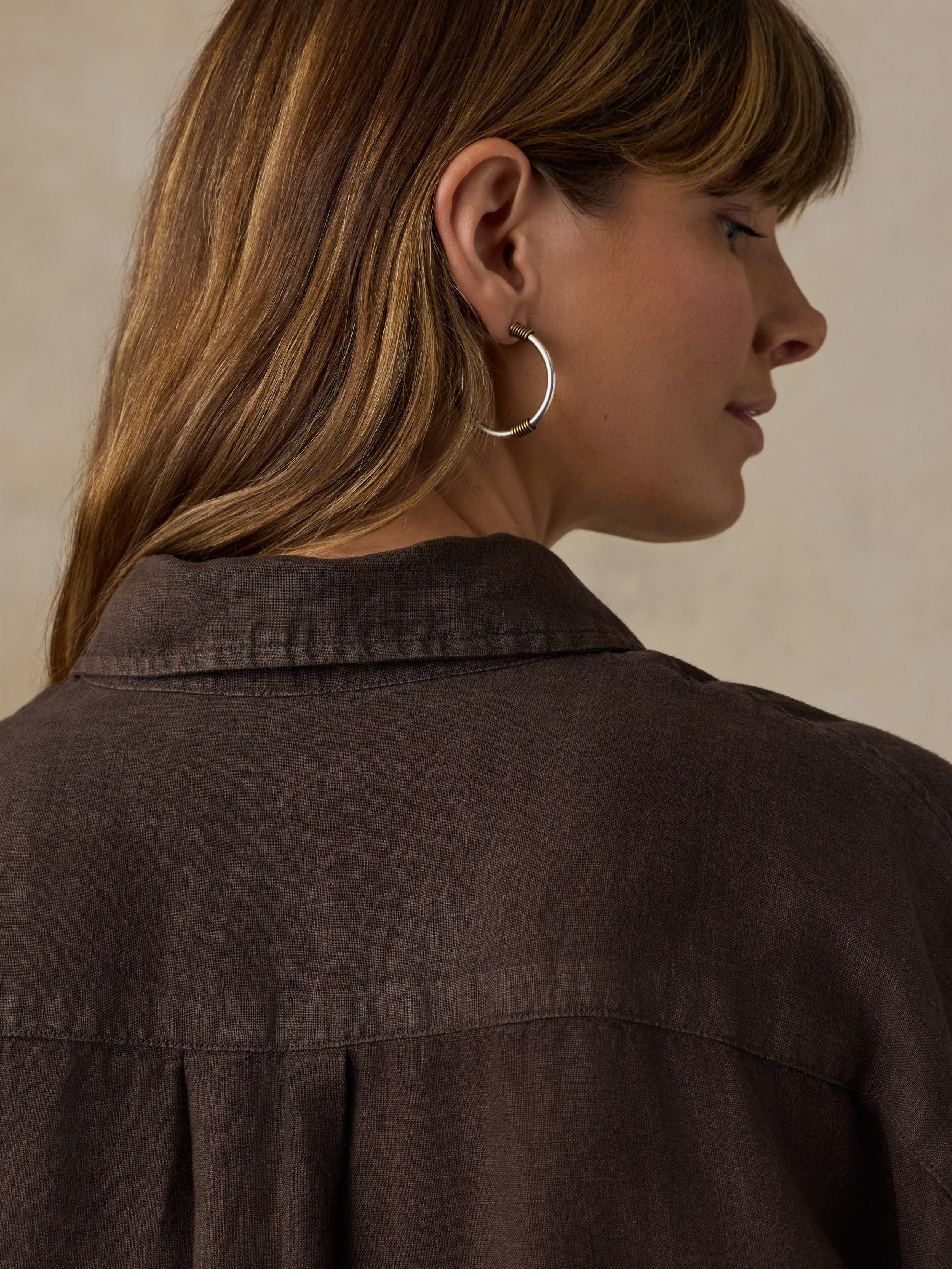 Woman wearing a brown linen shirt against a beige background