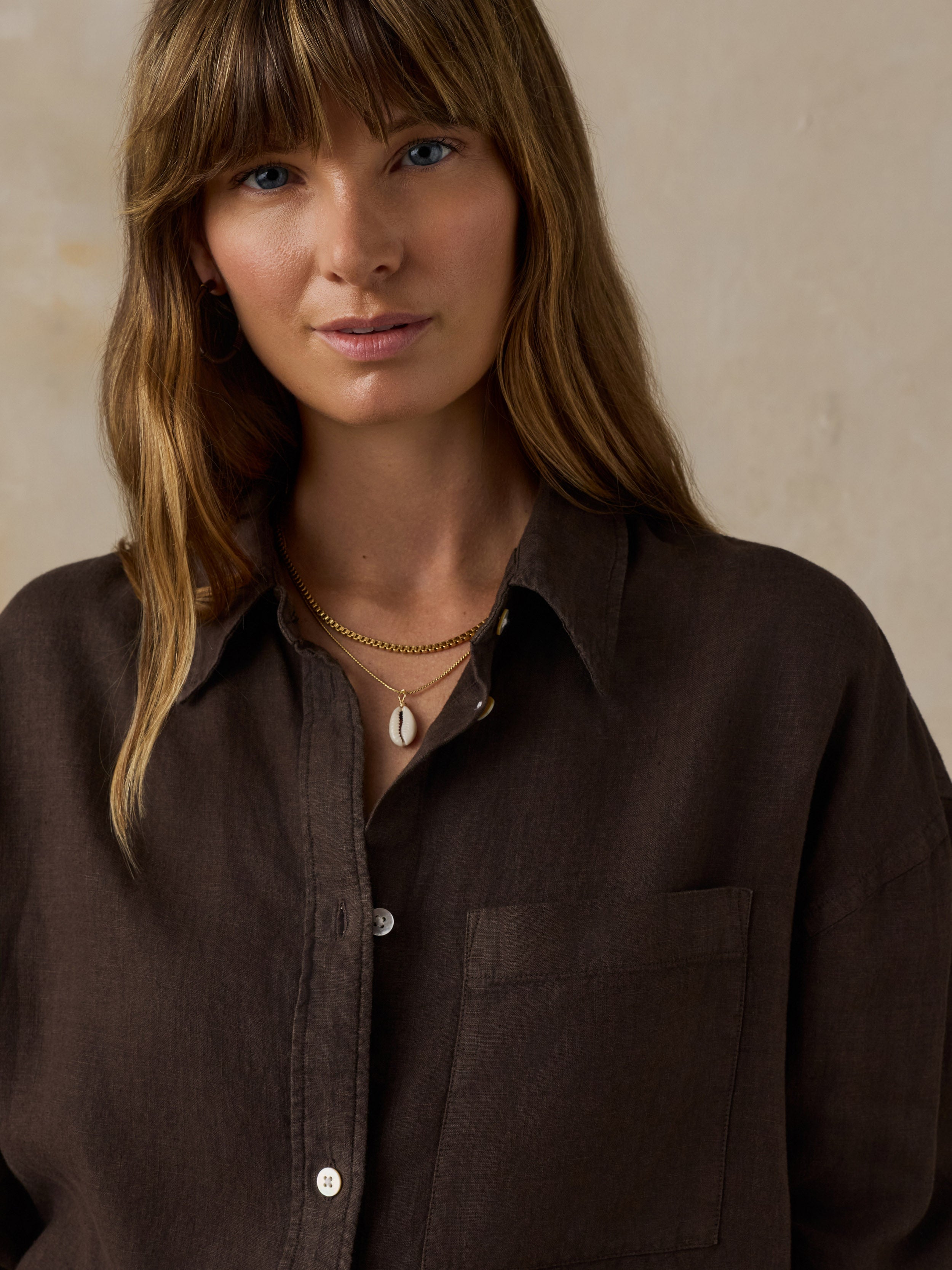 Woman wearing a brown linen shirt against a beige background