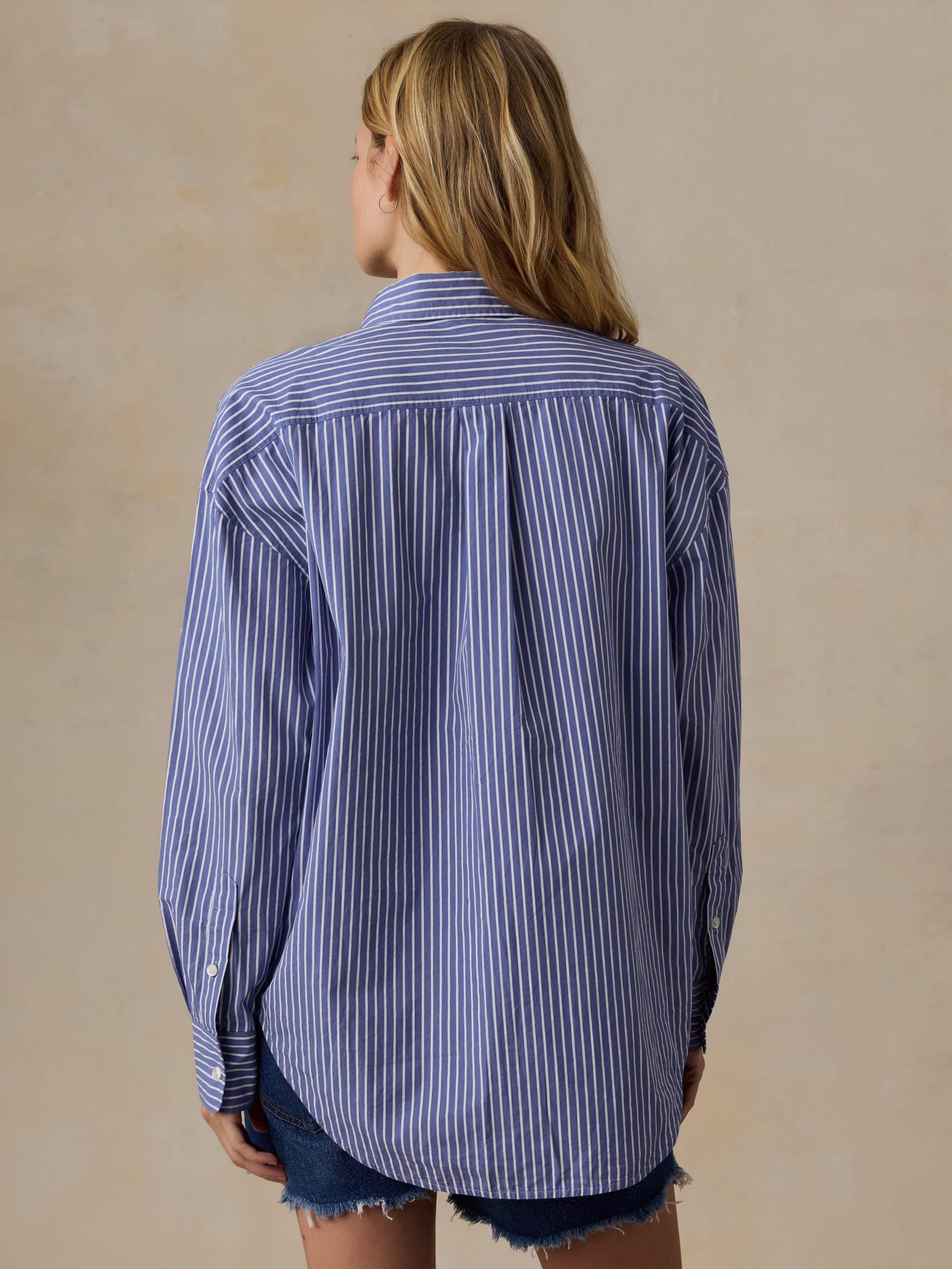 Woman wearing a blue and white striped shirt against a beige background
