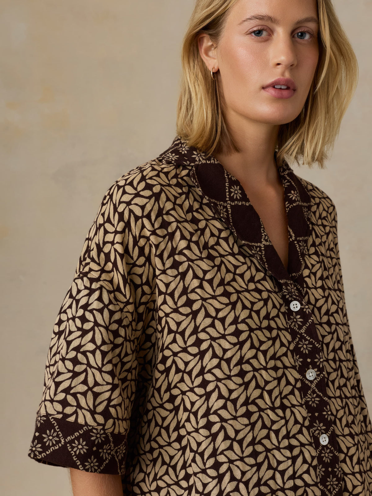Woman wearing a patterned shirt with a neutral background, image 4 of 5