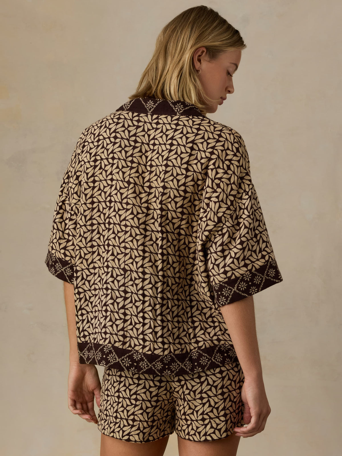 Woman wearing a patterned outfit against a beige background, image 5 of 5