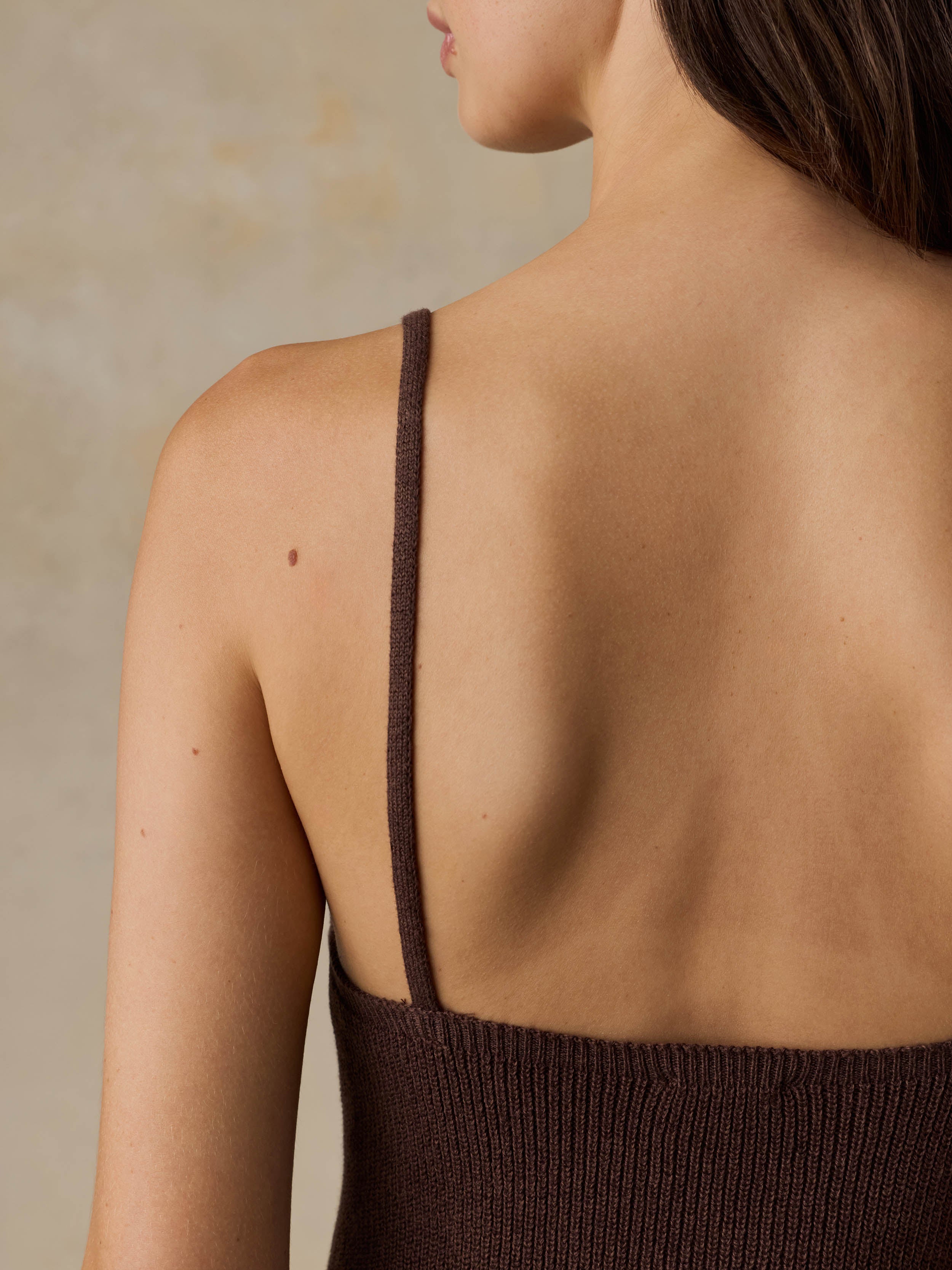 Woman wearing a brown tank top against a beige background