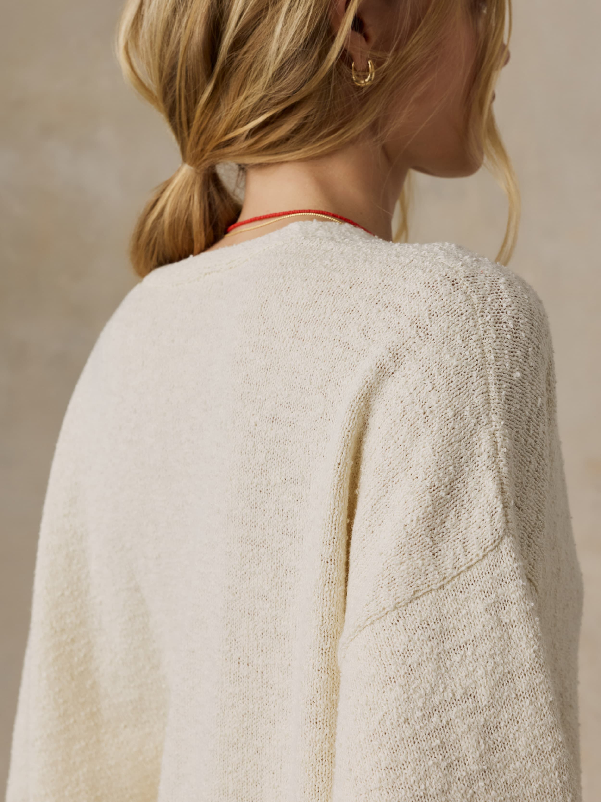 Woman wearing a cream sweater against a beige background