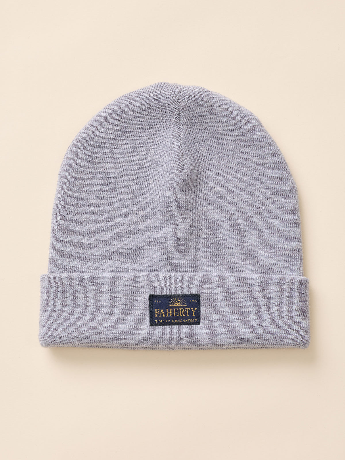 A light gray heather knit beanie hat with a folded cuff, featuring a small dark navy brand patch that reads 'PAHERTY' in gold lettering, set against a solid beige background., image 1 of 3