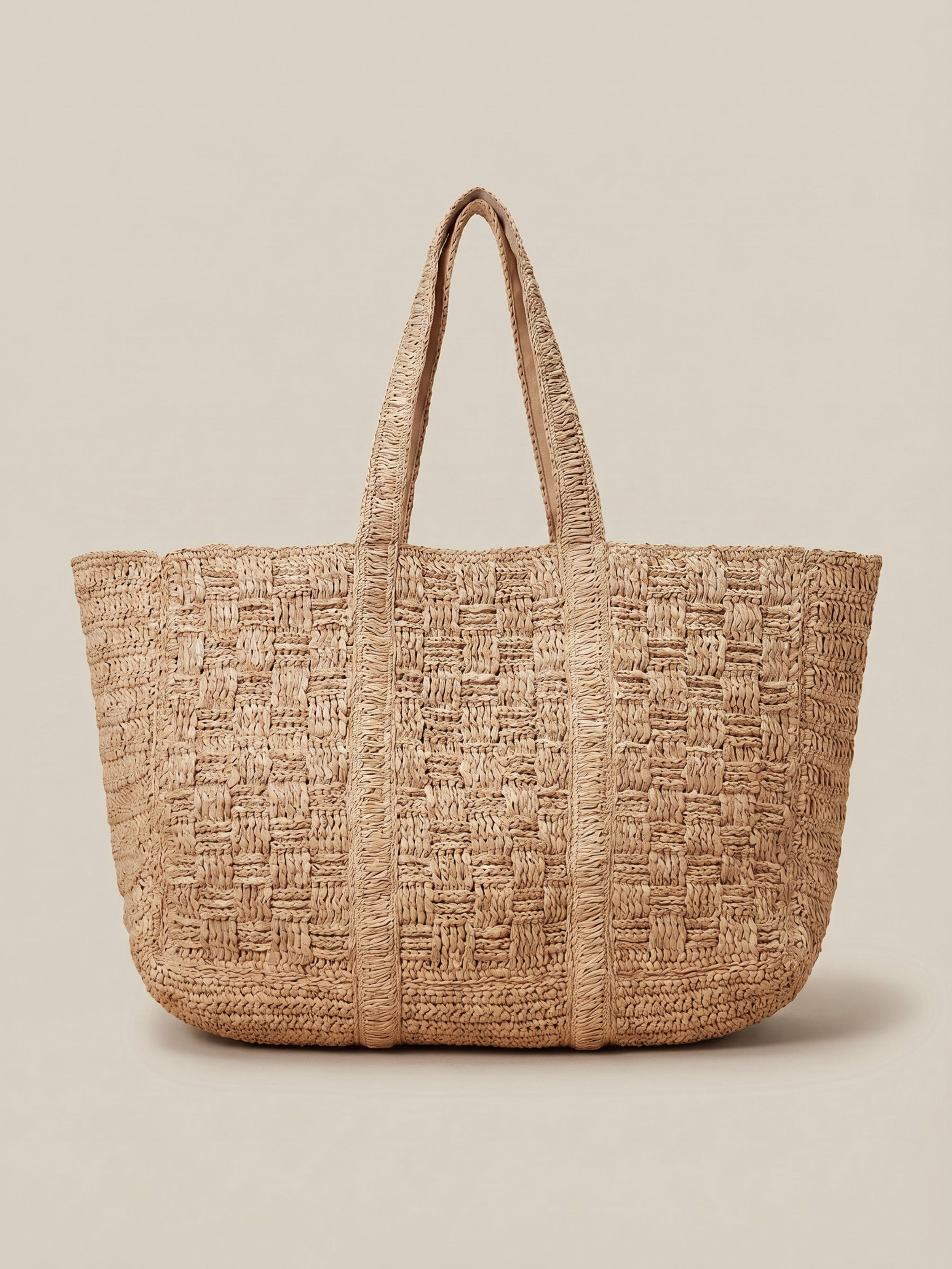 Woven straw tote bag on a beige background
