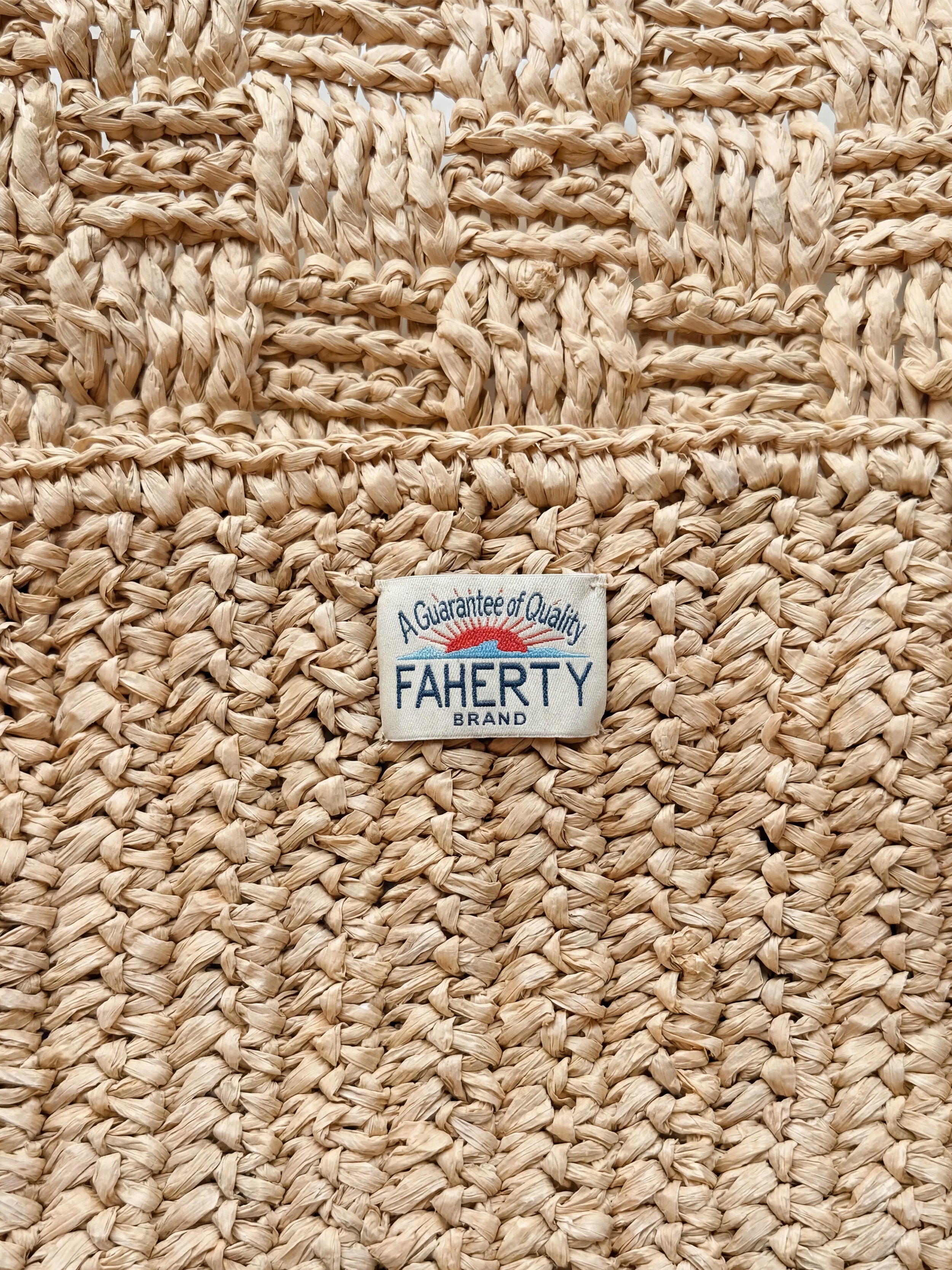 Close-up of a woven beige fabric with a 'Faherty Brand' label.