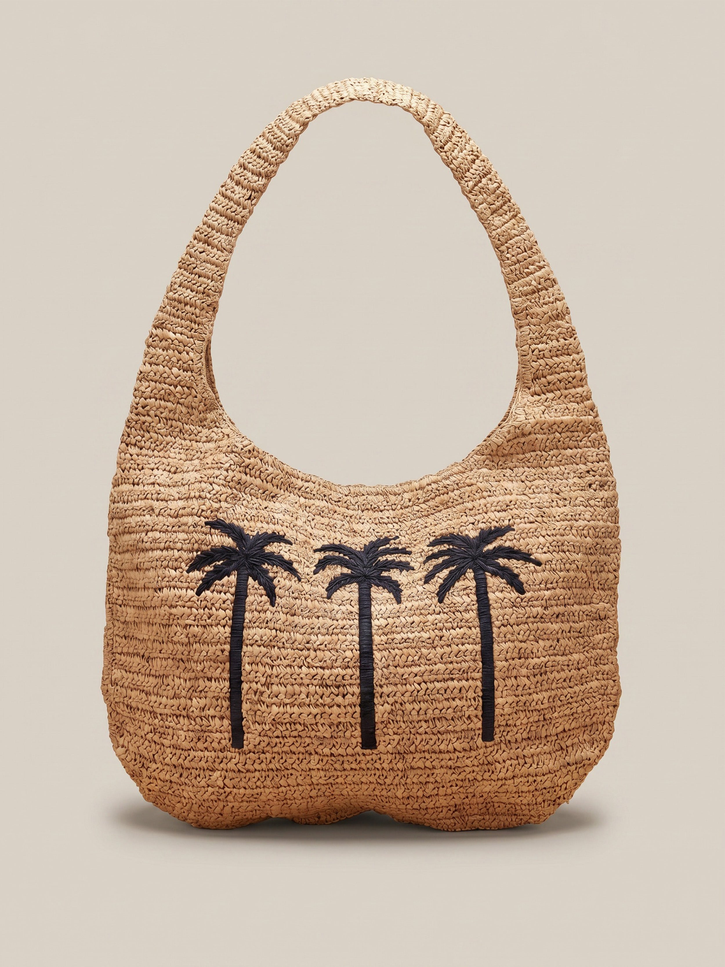 Raffia bag with palm tree graphic design on the front against a beige background