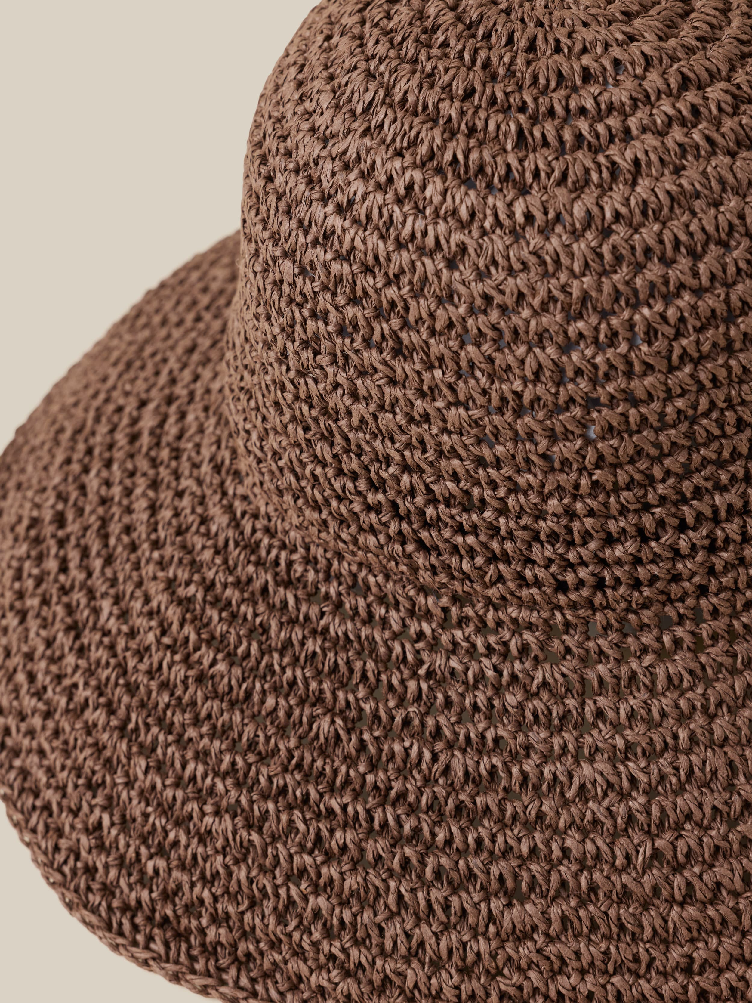 Close-up of a brown woven hat on a beige background