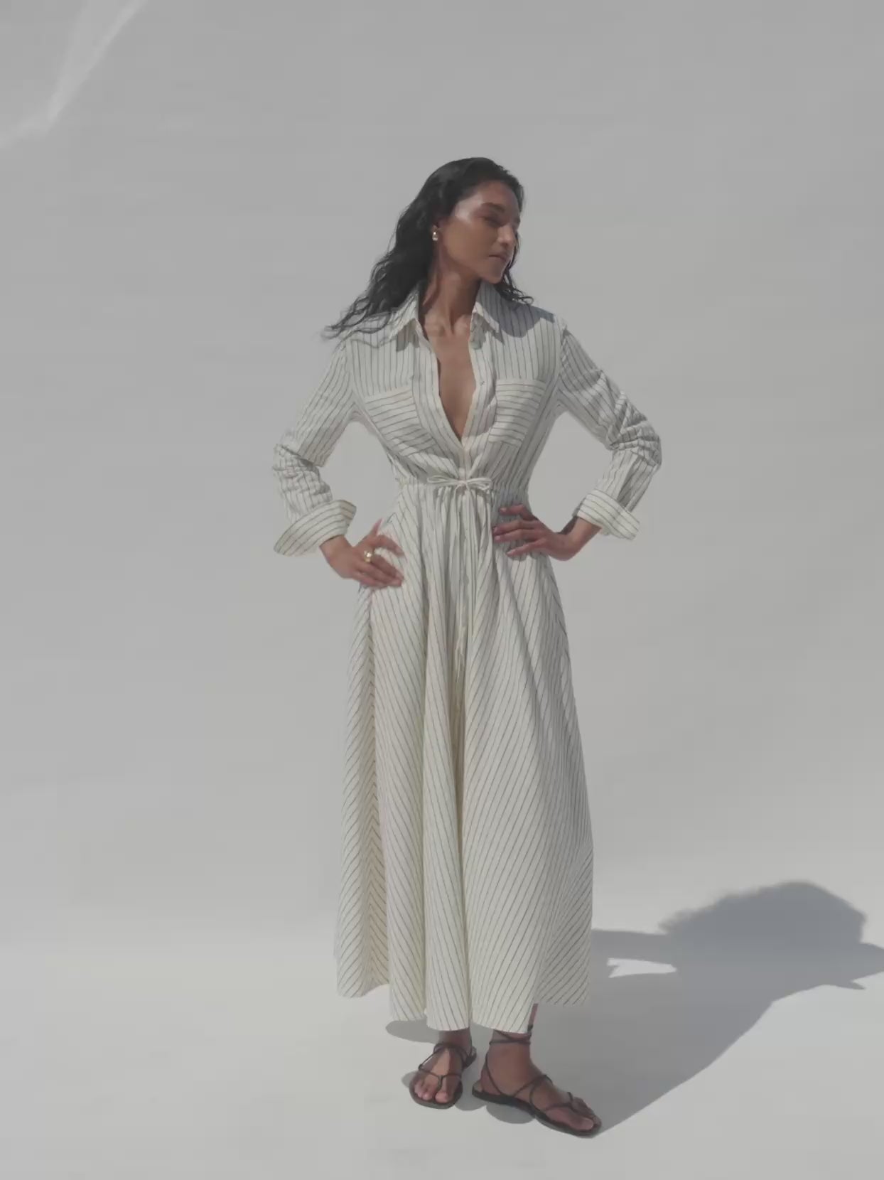 Video of a woman wearing a striped shirt dress against a white background