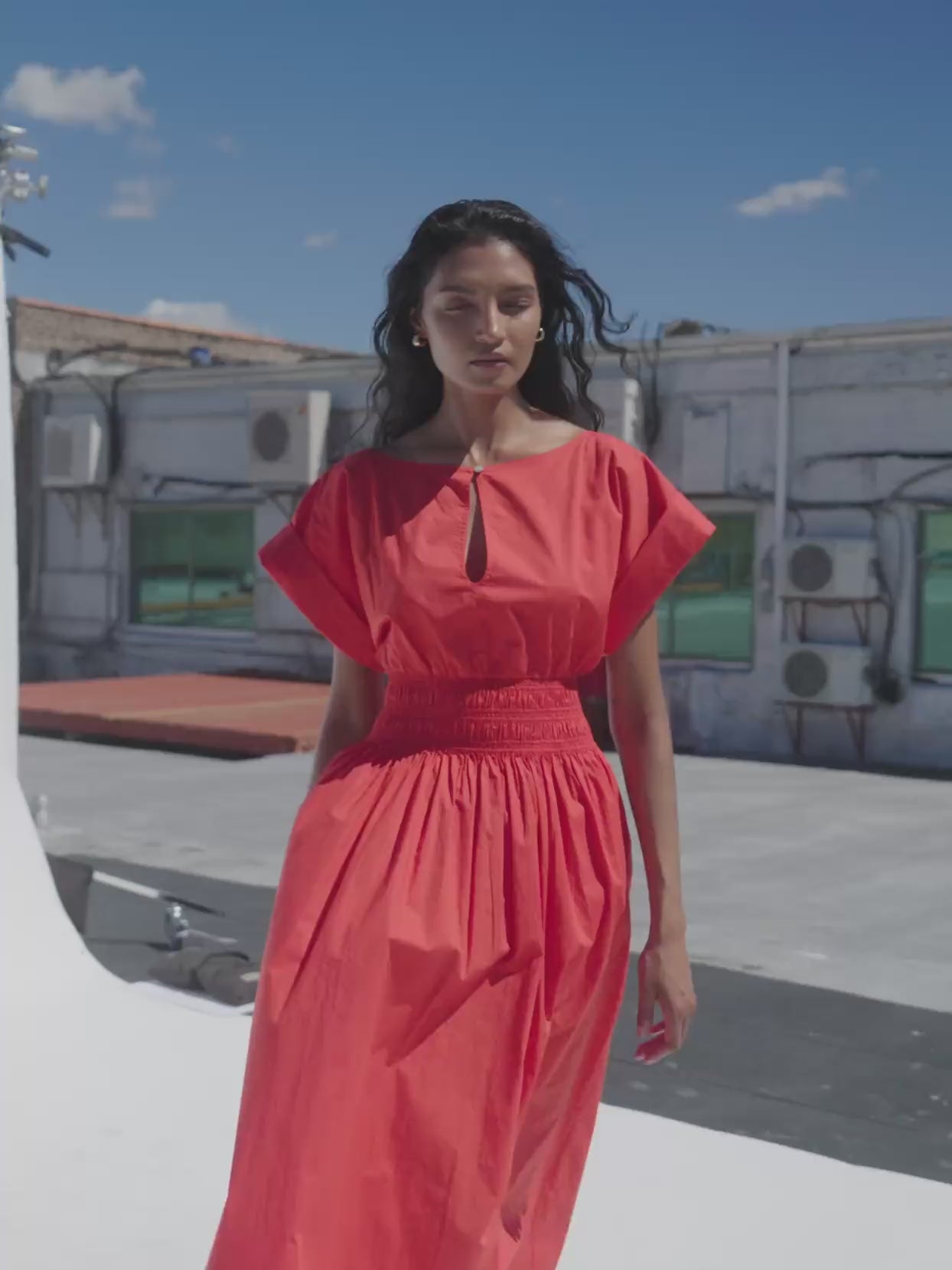 Video of a woman wearing a poppy red dress on a rooftop