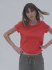 Video of a woman wearing a poppy red t-shirt with linen pants against a white background