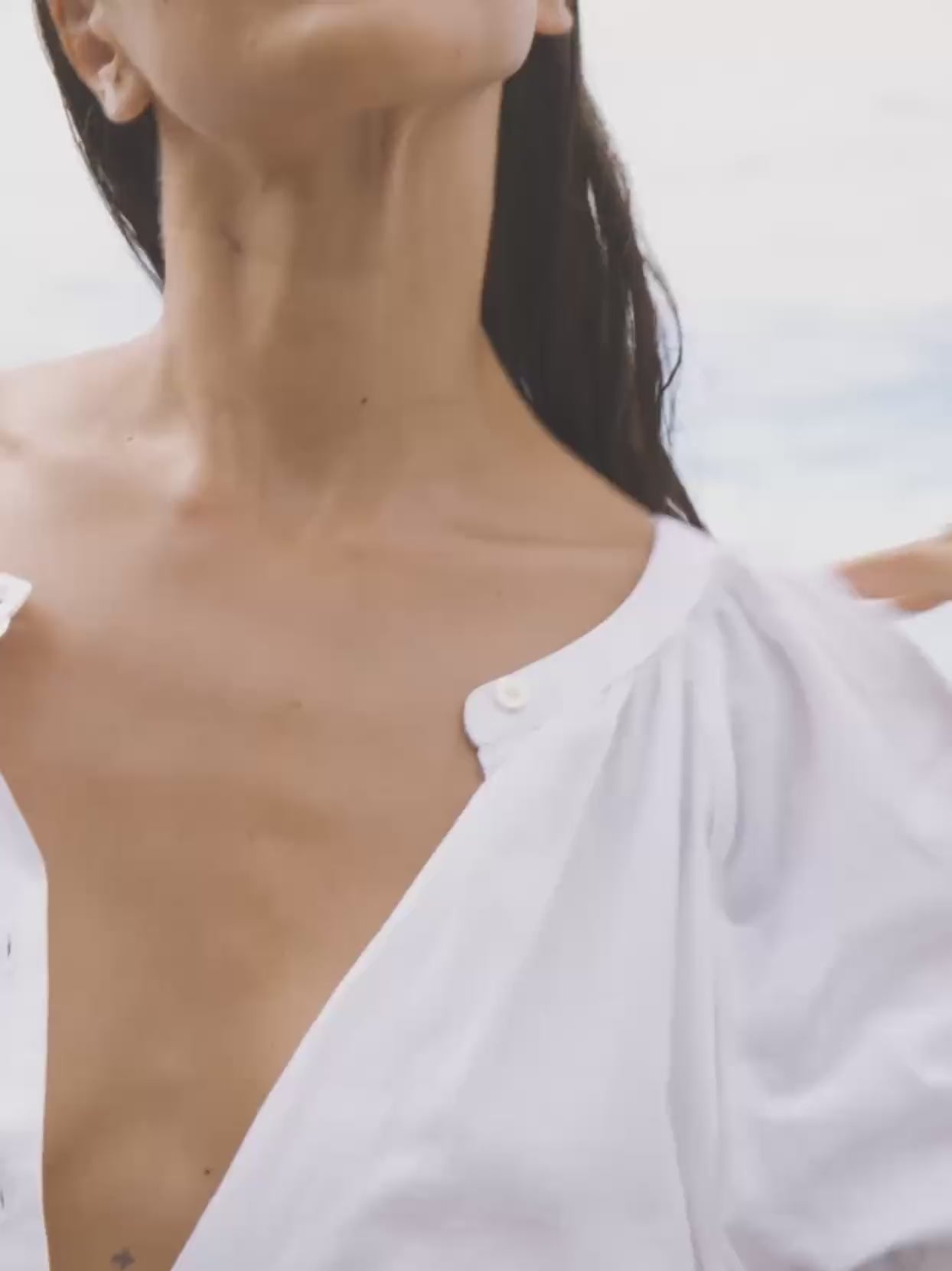 Video of a woman wearing a white top and denim shorts on the beach