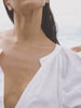 Video of a woman wearing a white top and denim shorts on the beach
