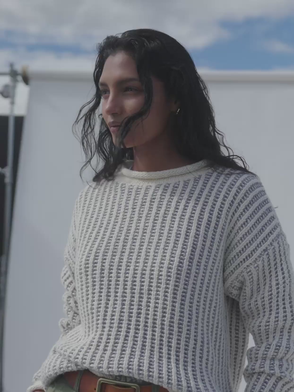Video of a woman wearing a white rollneck sweater against a white background