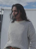 Video of a woman wearing a white rollneck sweater against a white background