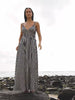 Video of a woman wearing a blue and white striped dress standing on rocks at the beach