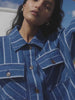 Video of a woman wearing a blue striped shirt and matching pants against a white background