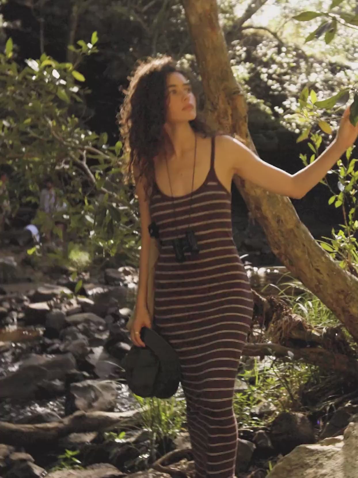 Video of a woman wearing a brown and white striped rib dress near a river.