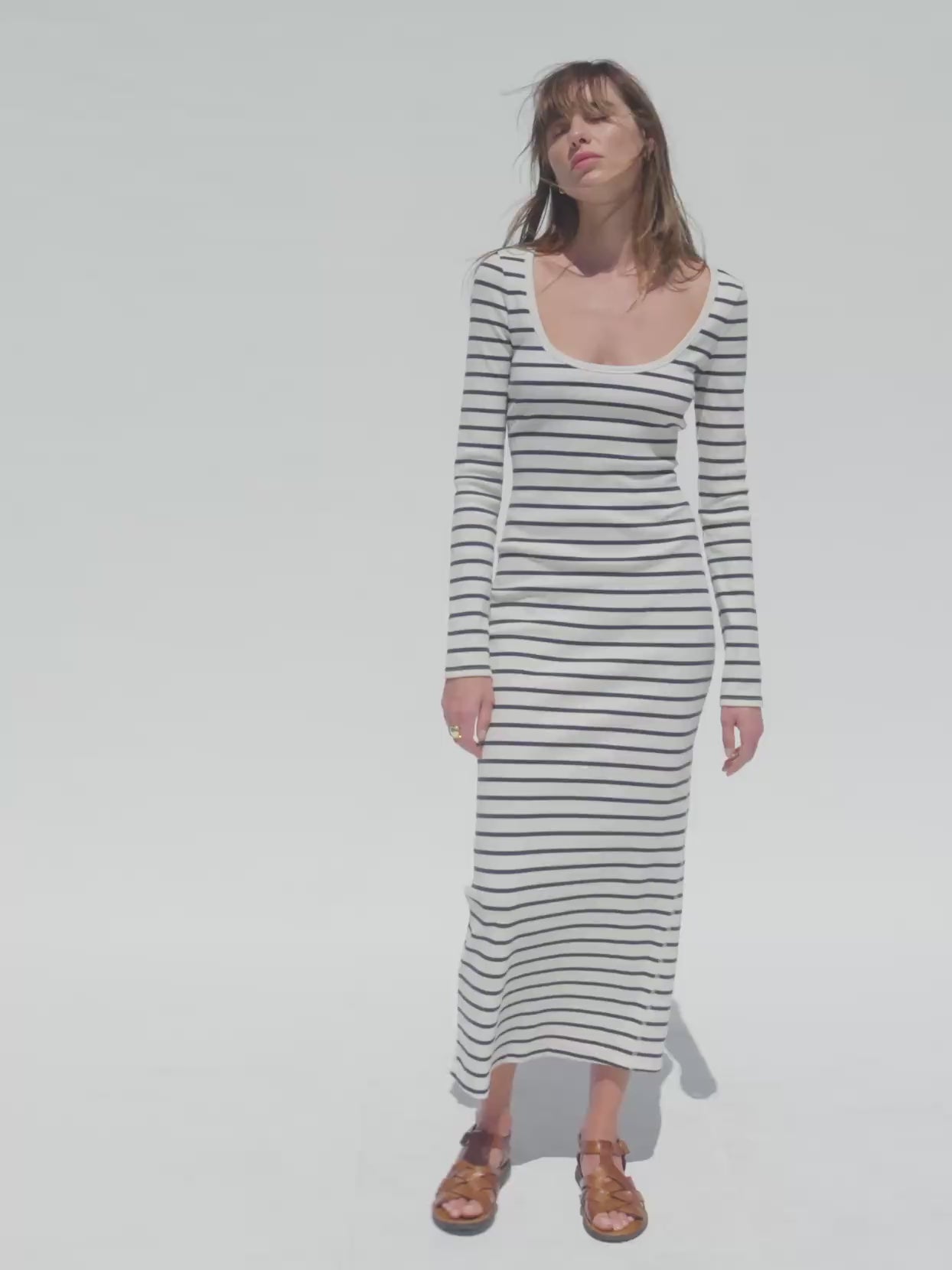 Video of a woman wearing a navy and white striped dress against a white background