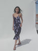 Video of a woman wearing a floral printed dress against a white background