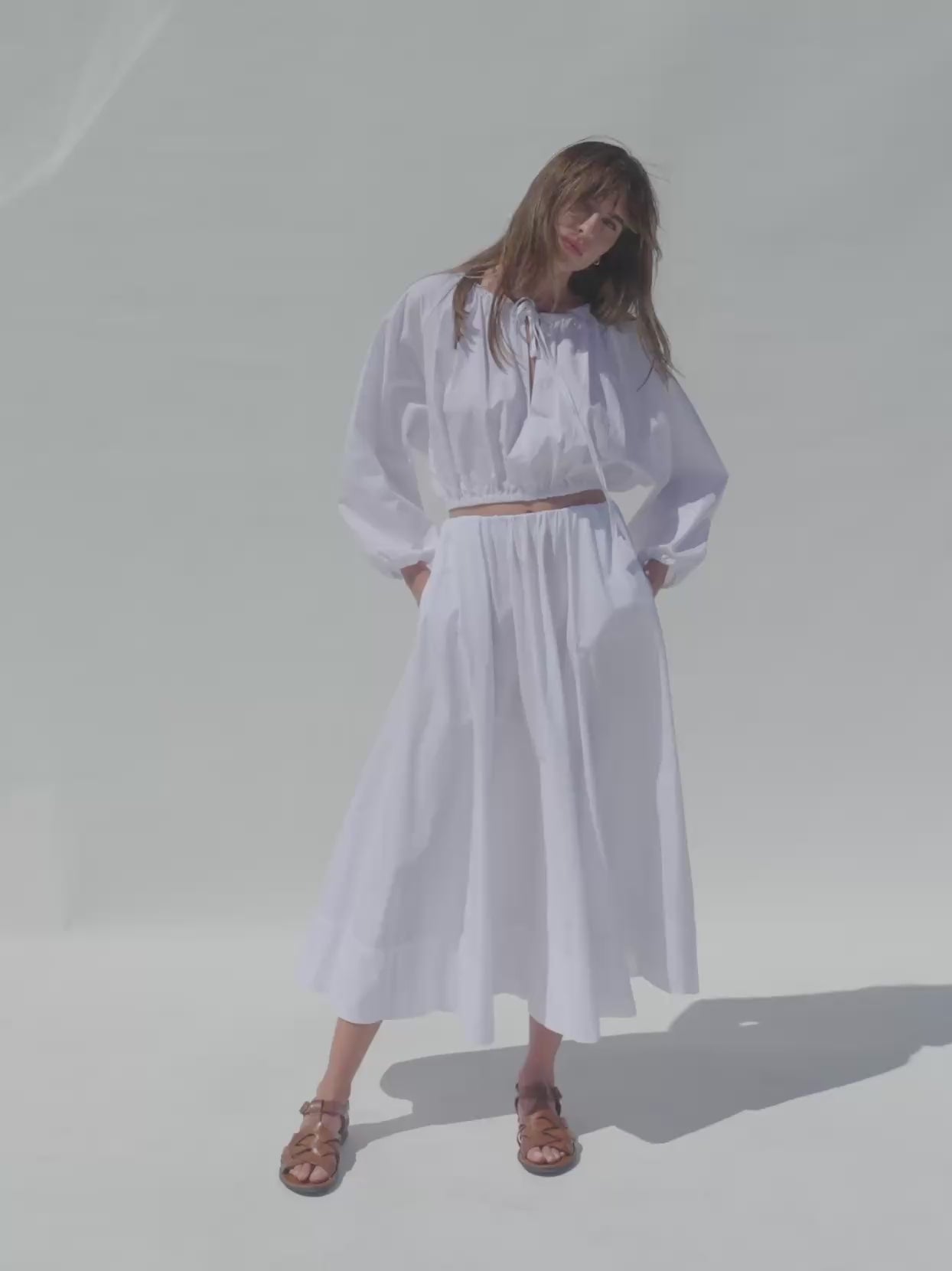 Video of a woman wearing a white poplin top with matching skirt against a white background