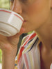 Video of a woman wearing a multicolor striped shirt and matching pants while sitting outside. 