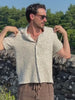 Man wearing a floral printed button up shirt and brown linen shorts standing outside in nature 