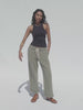 Video of a woman wearing a black tank top and olive green sweatpants against a white background