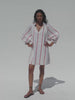 Video of a woman wearing a white dress with red stripes against a white background