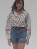 Video of a woman wearing a floral blouse with blue denim shorts against a white background