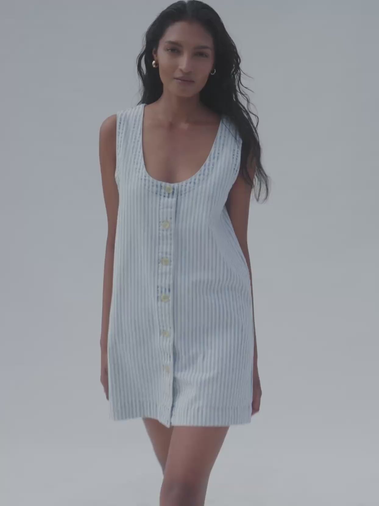 Video of a woman wearing a striped denim dress against a white background