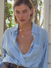 Video of a woman wearing a linen shirt and pants standing outside