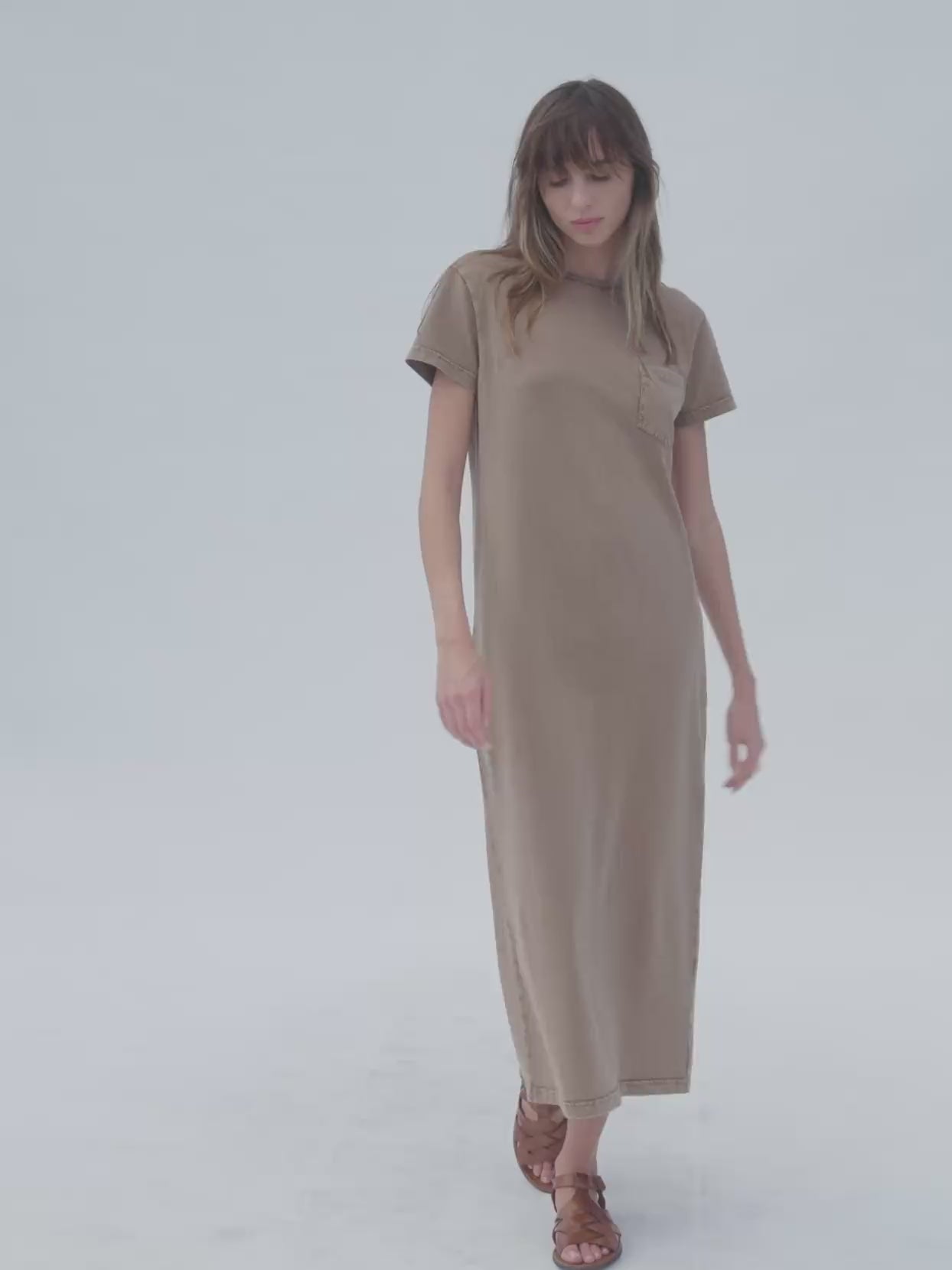 Video of a woman wearing a brown t-shirt dress against a white background