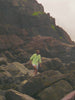 Man wearing a green hoodie with blue and white striped swim trunks at the beach