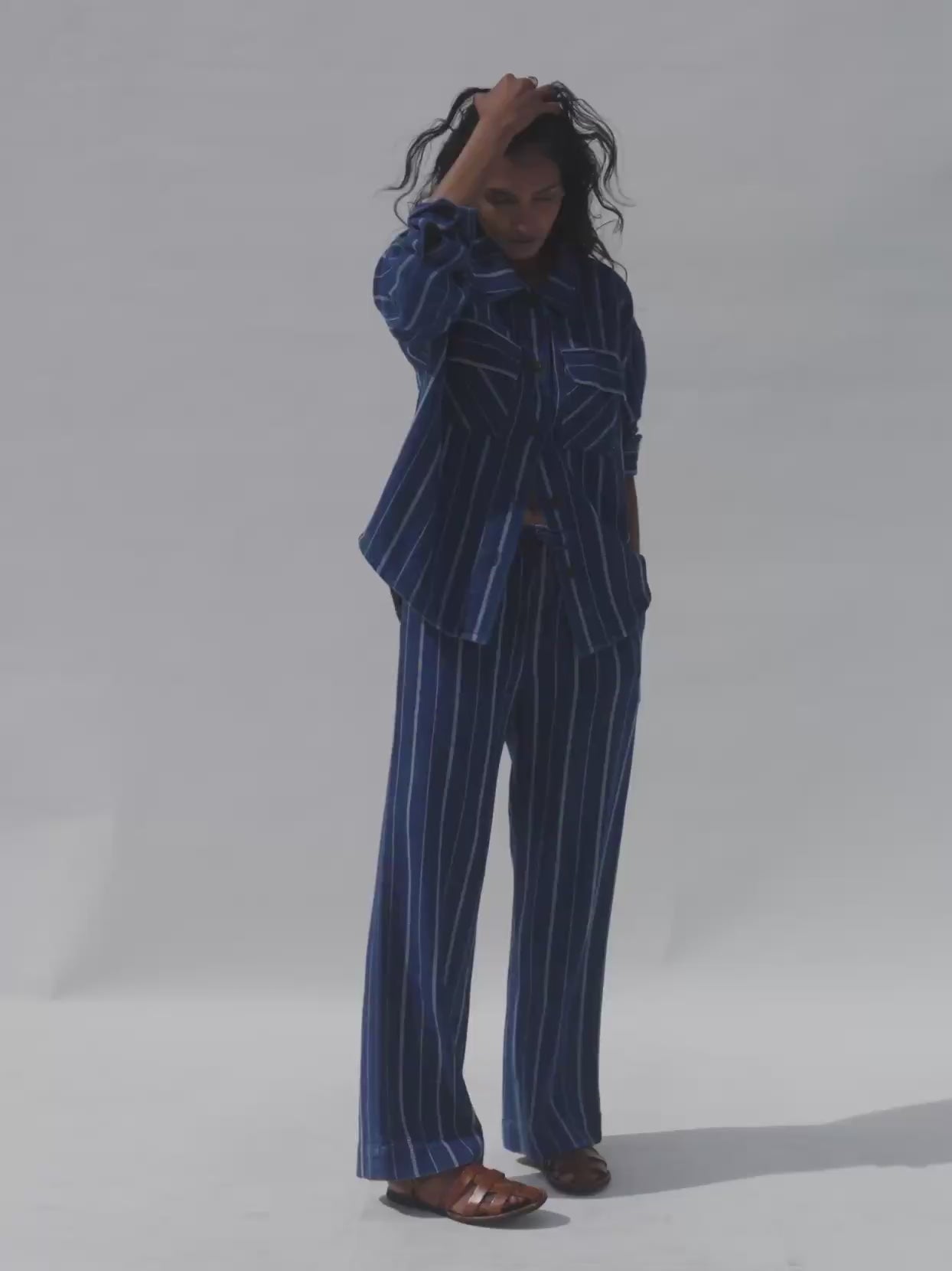 Video of a woman wearing a matching blue striped set against a white background