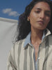 Video of a woman wearing a green striped linen shirt over a chambray shirt against a white background