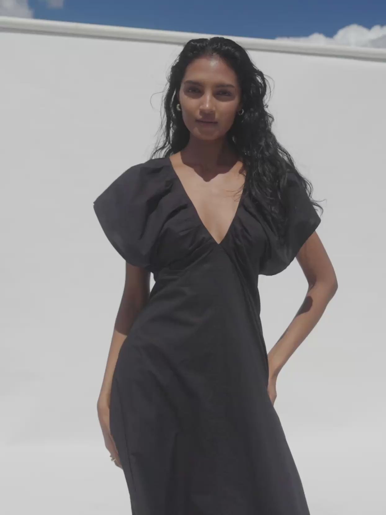Video of a woman wearing a black dress against a white background