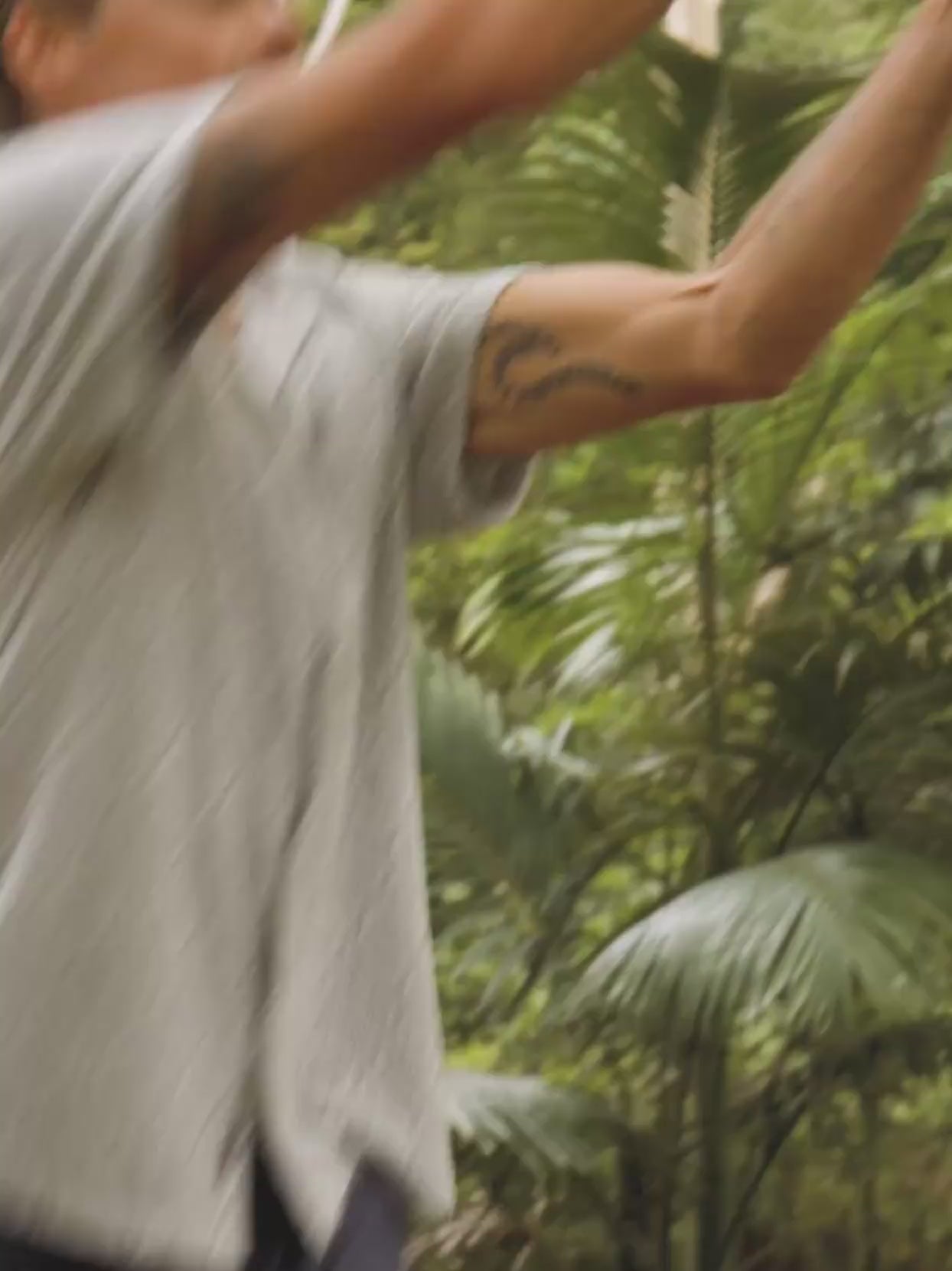 Video of a man wearing a patterned shirt and shorts in a forest