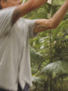 Video of a man wearing a patterned shirt and shorts in a forest