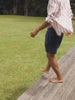 Video of a man wearing a striped long sleeve shirt and blue shorts walking in the grass