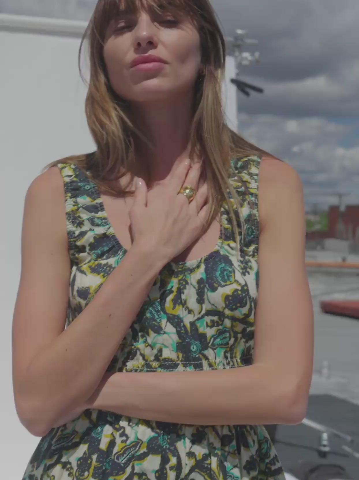 Video of a woman wearing a tropical print dress on a rooftop