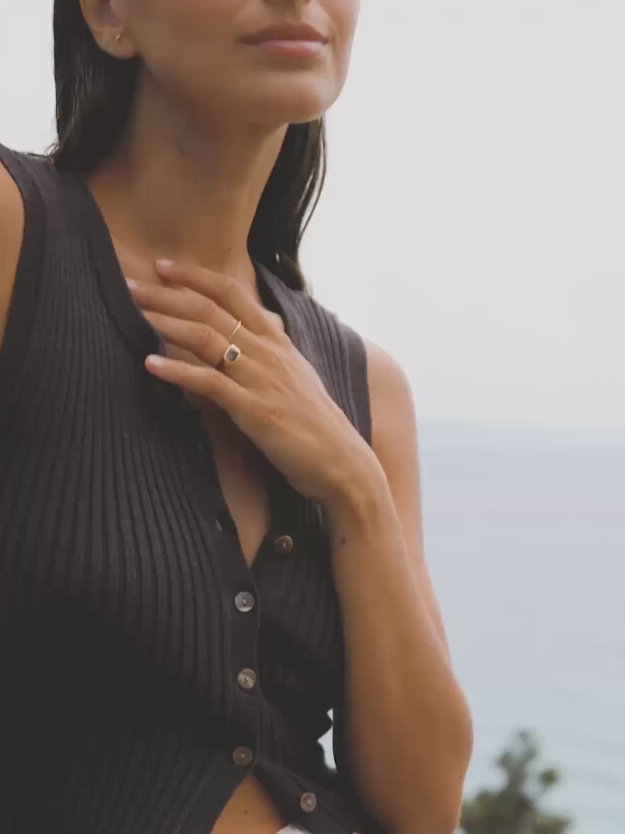 Video of a woman wearing a brown cami cardigan overlooking the ocean