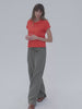 Video of a woman wearing a poppy red t-shirt with green linen pants against a white background