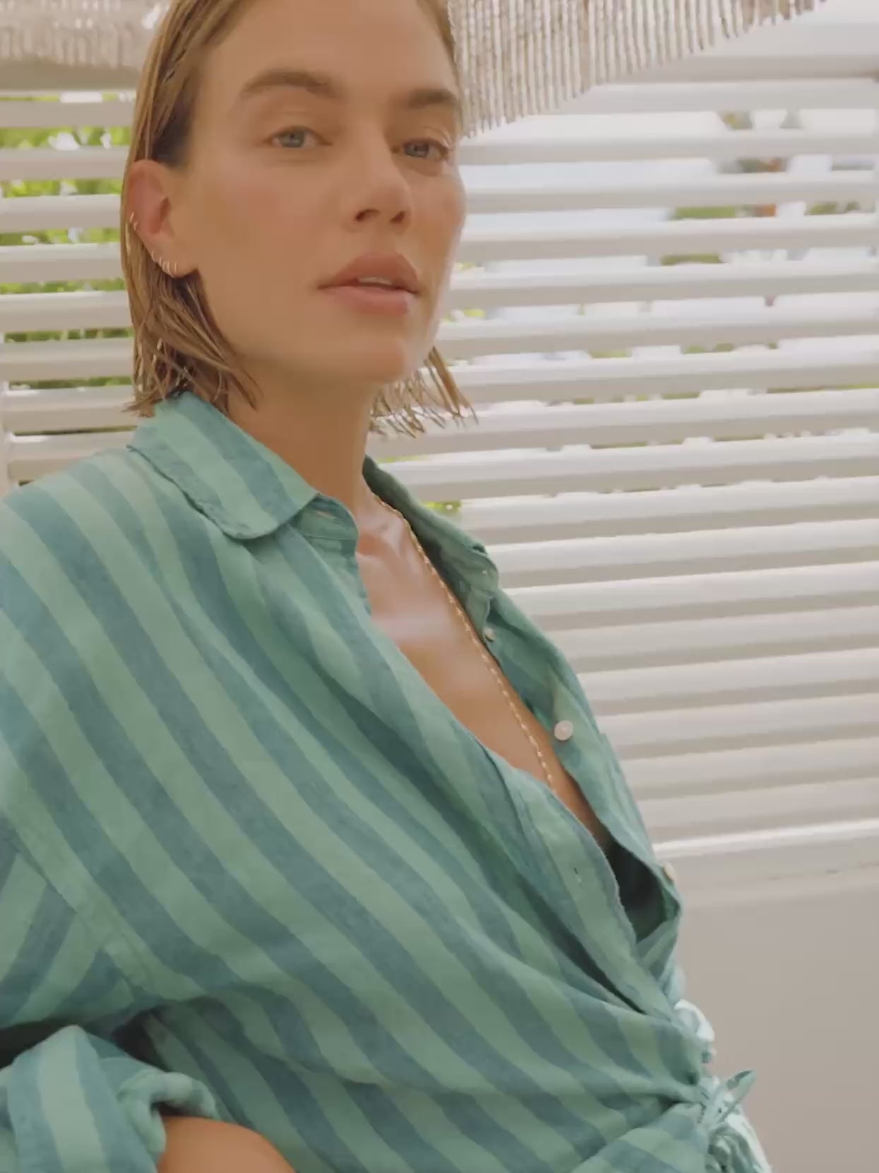 Video of a woman wearing a green striped linen shirt and matching shorts